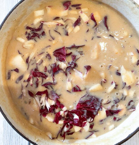 A pot of butter bean soup with red radicchio.